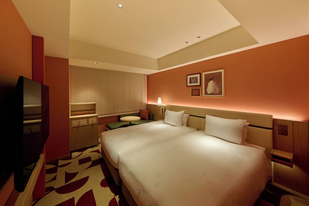 A hotel room with a large bed, a desk, a television, and a small table.