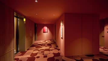 A hallway with patterned carpet, wooden paneling, and a red sign on the wall.
