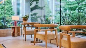 A modern indoor seating area with wooden chairs and a small table with a lamp and books. - The Royal Park Hotel Ginza 6-chome (Tokyo)