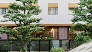 A modern building with a glass facade, large windows, and a tree in the foreground. - The Royal Park Hotel Ginza 6-chome (Tokyo)