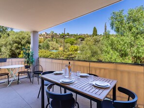 Une terrasse avec une table dressée pour le repas, des chaises et une vue sur la verdure et les collines.