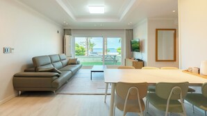 Un salon moderne comprenant un canapé, une table à manger, des chaises et un téléviseur.