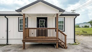 A small, single-story building with a porch and a door, surrounded by a gravel area.