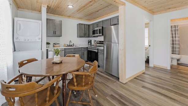 A modern kitchen with grey cabinets, stainless steel appliances, and a wooden dining table with chairs.