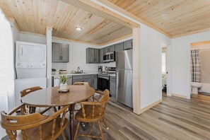 A modern kitchen with grey cabinets, stainless steel appliances, and a wooden dining table with chairs.