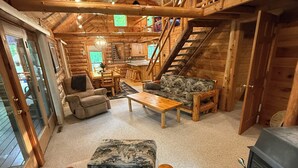A log cabin interior with a central seating area, a fireplace, and a staircase leading to an upper level. - LABOR DAY SALE-Private Trillium Lake Log Cabin-Sauna & Nature Escape (Hackensack)