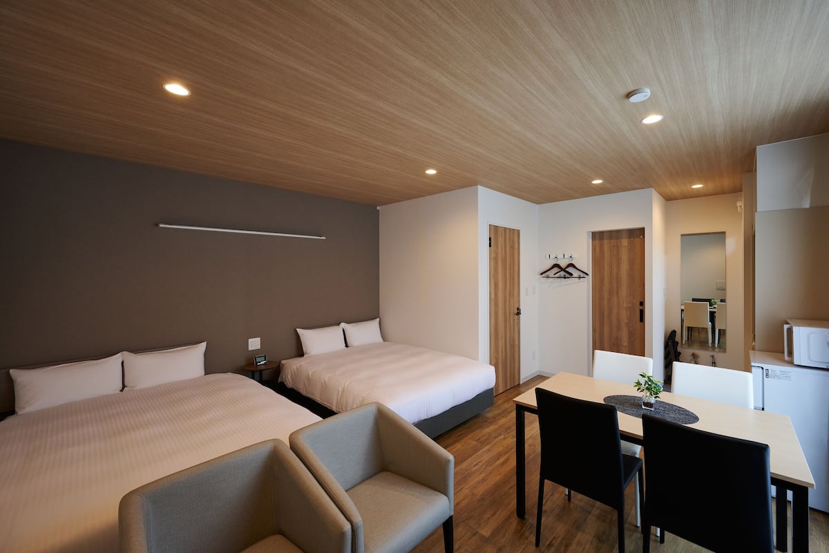 A hotel room with two beds, a desk, and a chair.