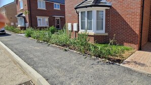 A residential street with houses, a driveway, and a small garden area. - Peterborough - House - Sleeps 8 - Parking - Garden (Peterborough)