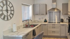 A modern kitchen with a marble countertop, stainless steel appliances, and light-colored cabinetry. - Peterborough - House - Sleeps 8 - Parking - Garden (Peterborough)