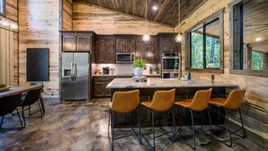 Une cuisine moderne avec des murs en bois, des appareils électroménagers en acier inoxydable et un îlot central doté de tabourets de bar.
