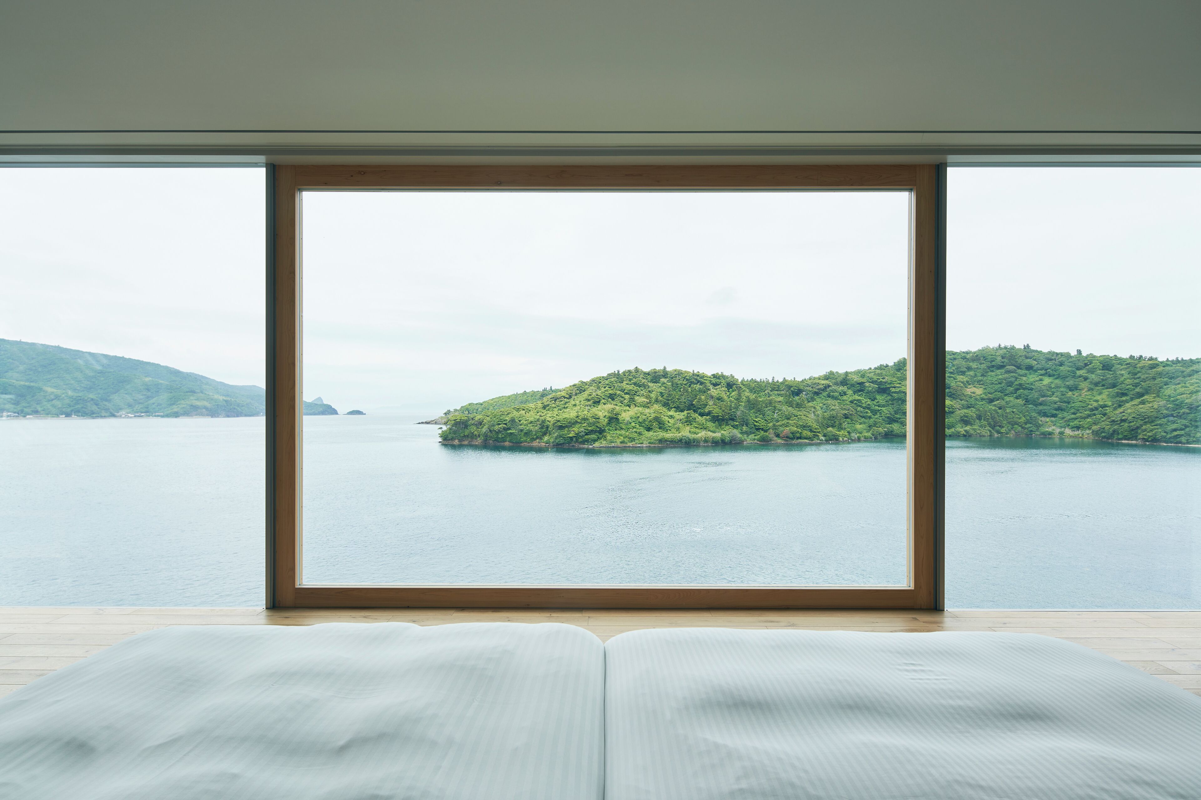 A room with a large window overlooking a body of water and a green island.
