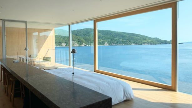 Una camera moderna con un letto grande, un tavolo lungo e vista sul mare e sulle colline.