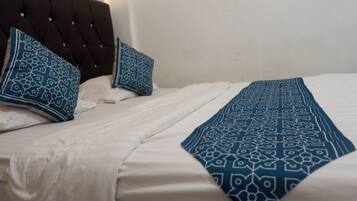 Un lit bien fait, avec du linge de lit blanc et des coussins et un couvre-lit à motifs bleus.