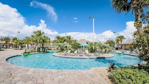 A pool area with lounge chairs, palm trees, and a central water feature. - Solterra Resort 6 bed home, 20 mins to Disney, 5 mins to Championsgate! (Davenport)