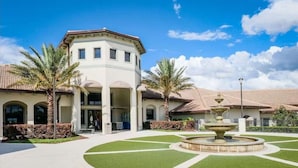 A hotel with a central courtyard, palm trees, and a fountain. - Solterra Resort 6 bed home, 20 mins to Disney, 5 mins to Championsgate! (Davenport)