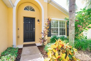 Stunning residential building with a charming entrance, surrounded by lush greenery and vibrant plants.