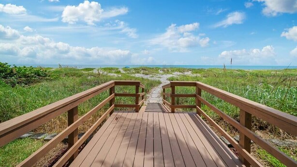 A wooden boardwalk leading to a beach with a clear sky. - Dream Beach Home Vacation - Direct Beach Access & Exquisite Waterfront Views (Cocoa Beach)