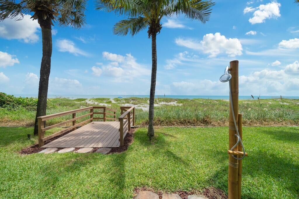 Un pontile in legno con ringhiera, palme e una vista libera sulla spiaggia.