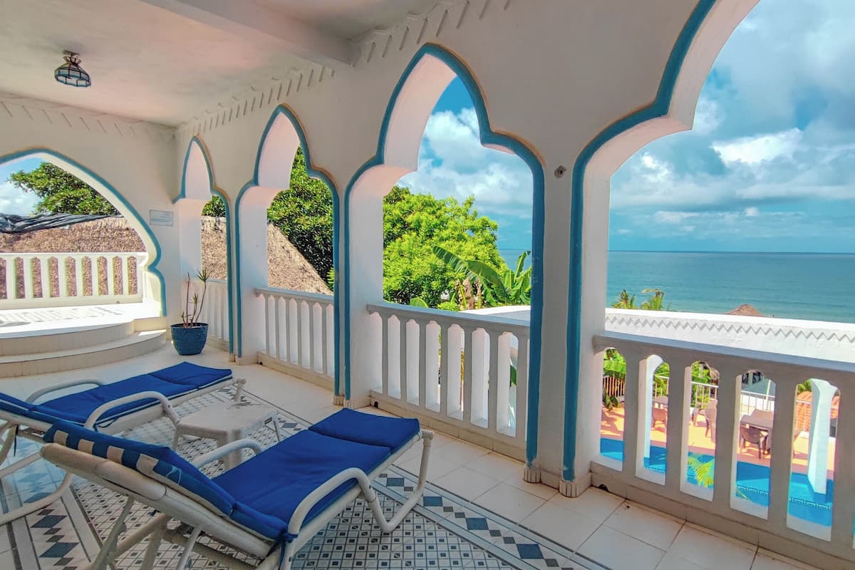 A covered outdoor area with lounge chairs and a view of the sea.