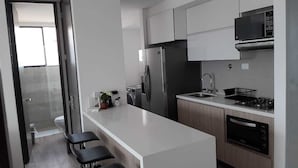 A modern kitchen with a white countertop, stainless steel appliances, and a built-in oven. - Diagonal 29d (Medellín)