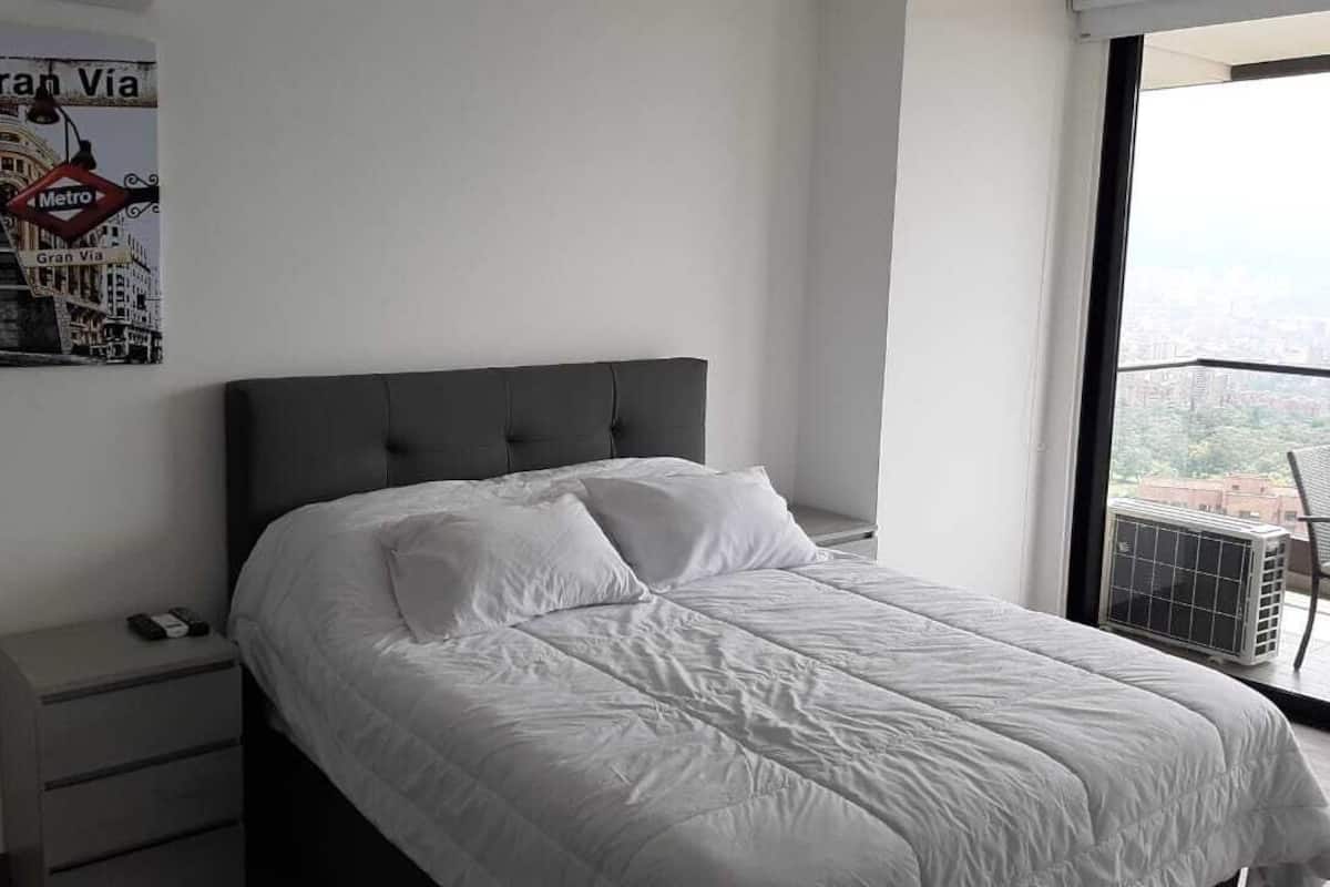 A bedroom with a bed, a nightstand, and a poster on the wall.
