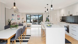 Une cuisine moderne avec des meubles blancs, un îlot central et des luminaires suspendus.