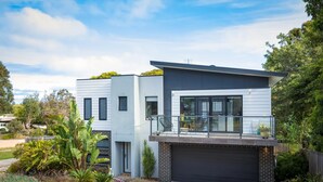 Une maison moderne à deux étages, dotée d’un grand garage, d’un balcon et d’un jardin bien entretenu.