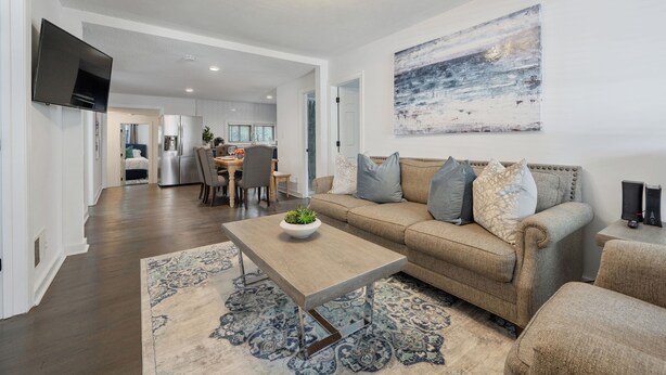 A spacious living room with a large sofa, a coffee table, and a flat-screen TV mounted on the wall. - Walk to Downtown~3 King Beds~Private Office (Raleigh)