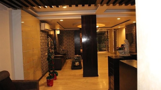 Un vestíbulo con pared de ladrillo, un árbol de Navidad, un mostrador de recepción y una estatua.