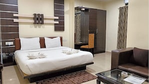 Una habitación de hotel con cama, escritorio, silla, sofá y armario.