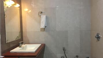 A bathroom with a sink, mirror, towel rack, shower, and toilet.
