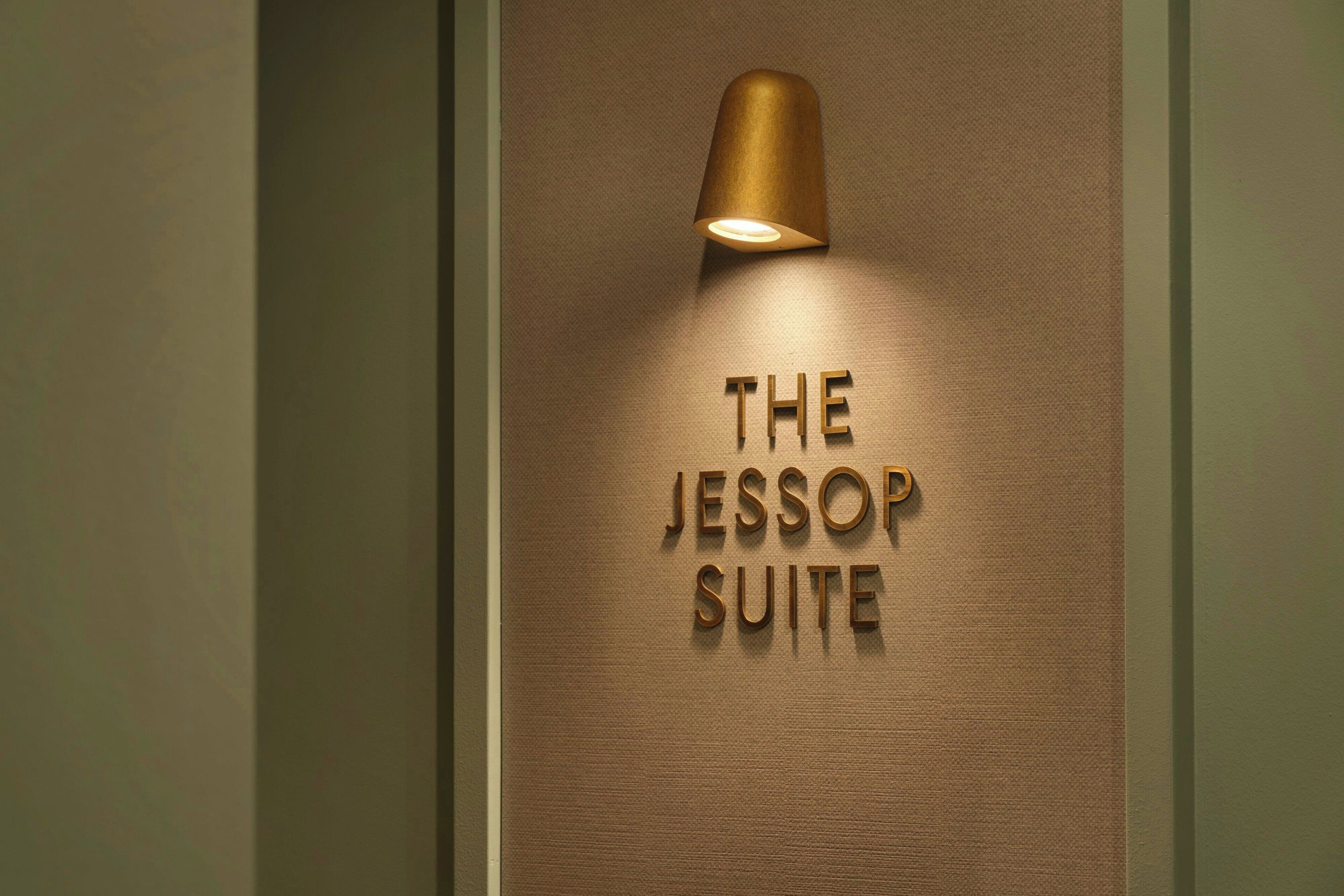 A wall with the text "THE JESSOP SUITE" illuminated by a light fixture.