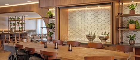 A modern kitchen with a wooden bar area, bar stools, and a hexagonal patterned backsplash.