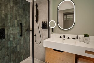 Un baño moderno con ducha, lavamanos y espejo.