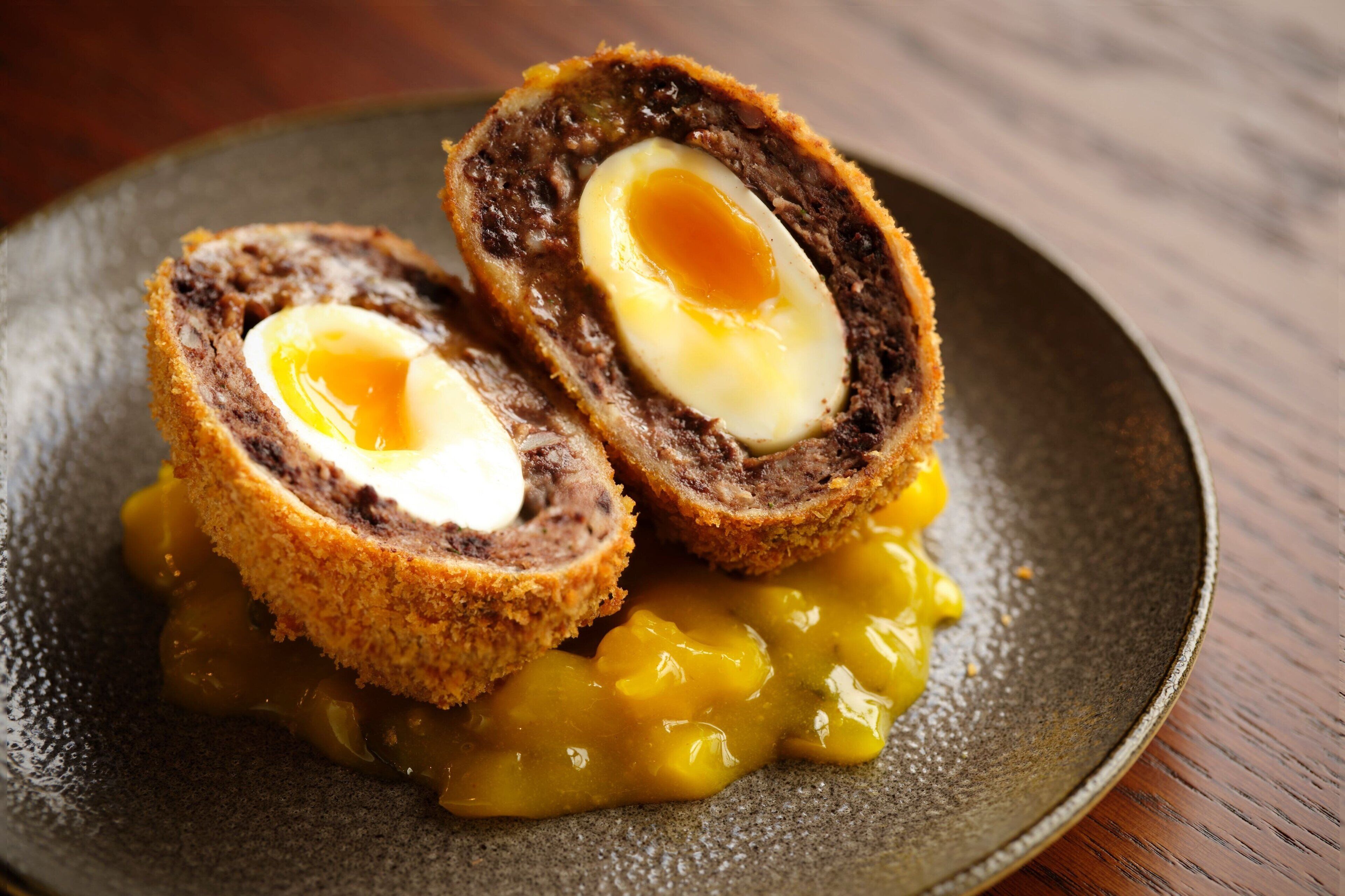 Een gerecht met een gerolde ei-vulling en vlees, geserveerd met een gele saus.