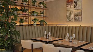 Een restaurantinterieur met zitjes, tafels en potplanten.