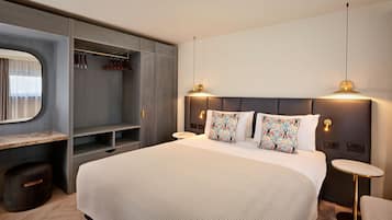 Una moderna camera da letto con un letto grande, un armadio a muro, un comodino e un piccolo tavolino rotondo.