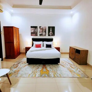 Cozy retreat with a large bed, wooden wardrobe, and cabinet, plus framed pictures on the wall.