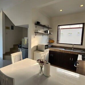 Enjoy meals at the dining table, surrounded by a vase of fresh flowers, and access to a microwave and refrigerator.