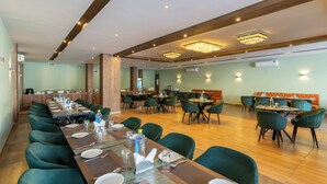 Un salón de conferencias con una larga mesa dispuesta para una reunión, rodeado de sillas verdes.