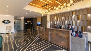 Zona de recepción de un hotel con diseño moderno, que presenta un techo de madera, un mostrador de recepción y un área de registro.