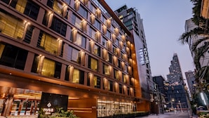 Un hotel moderno con un llamativo letrero 'NYSA', grandes ventanales y una fachada bien iluminada.