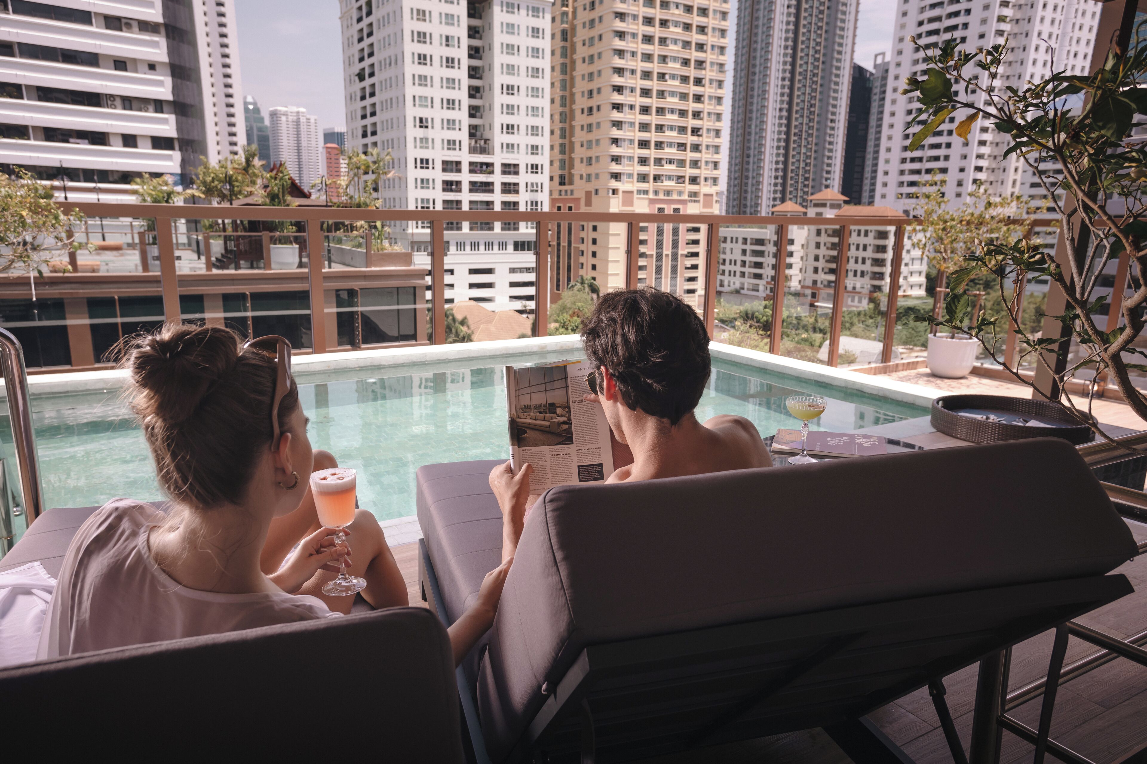 A rooftop pool area with lounge chairs and a glass barrier.