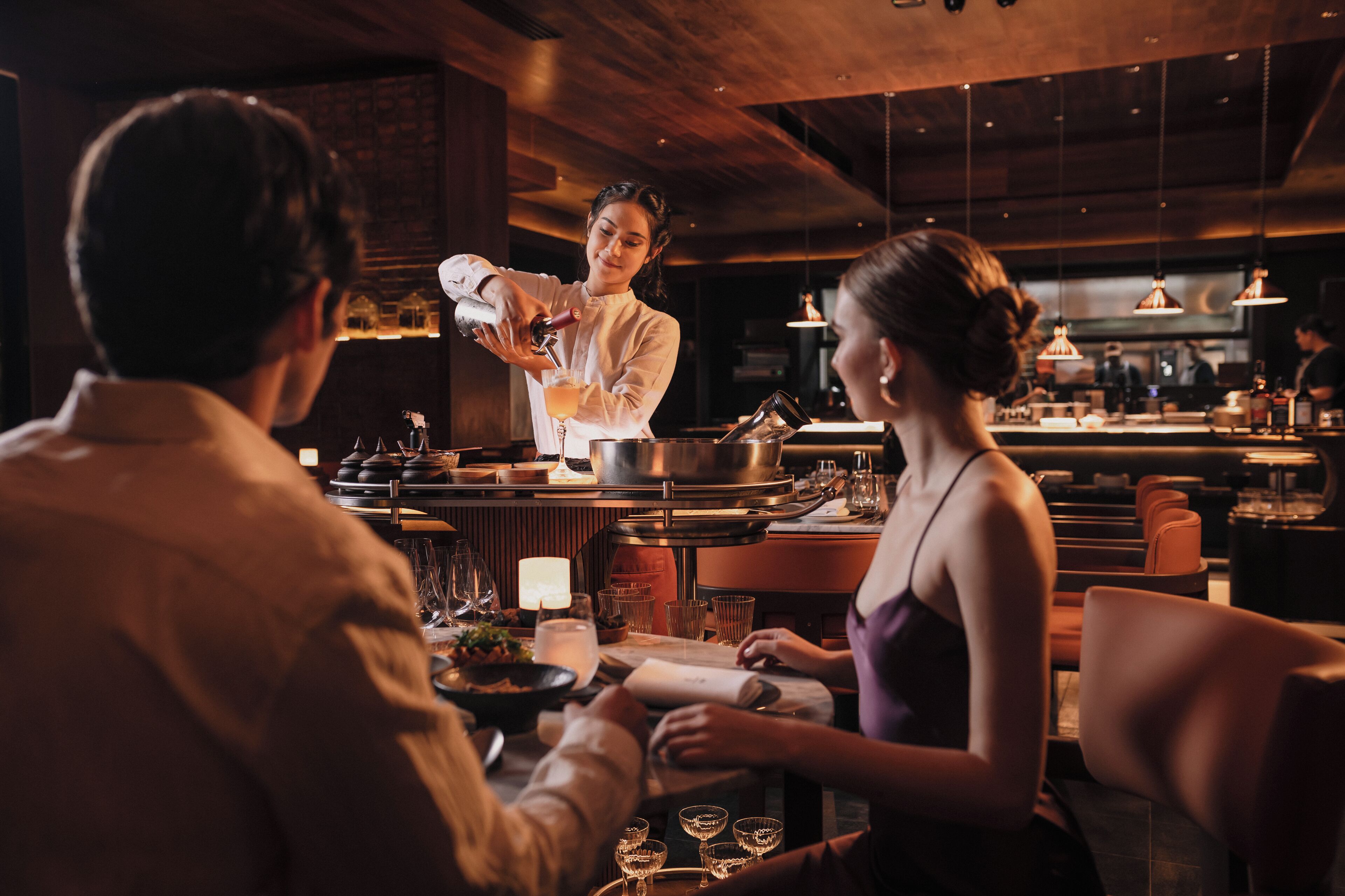 A restaurant interior with a bar area, wooden ceiling, and modern lighting fixtures.
