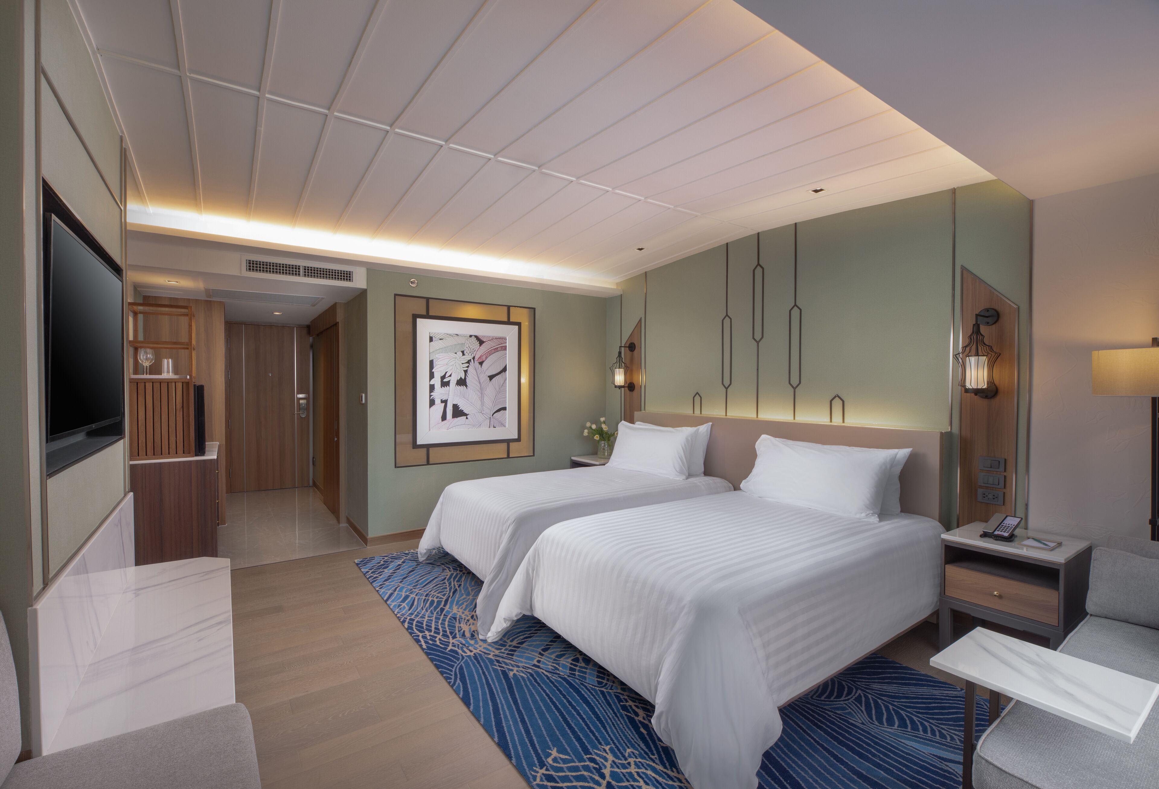 Ein Hotelzimmer mit zwei Betten, einem Fernseher, einem Schreibtisch und einem Badezimmer.