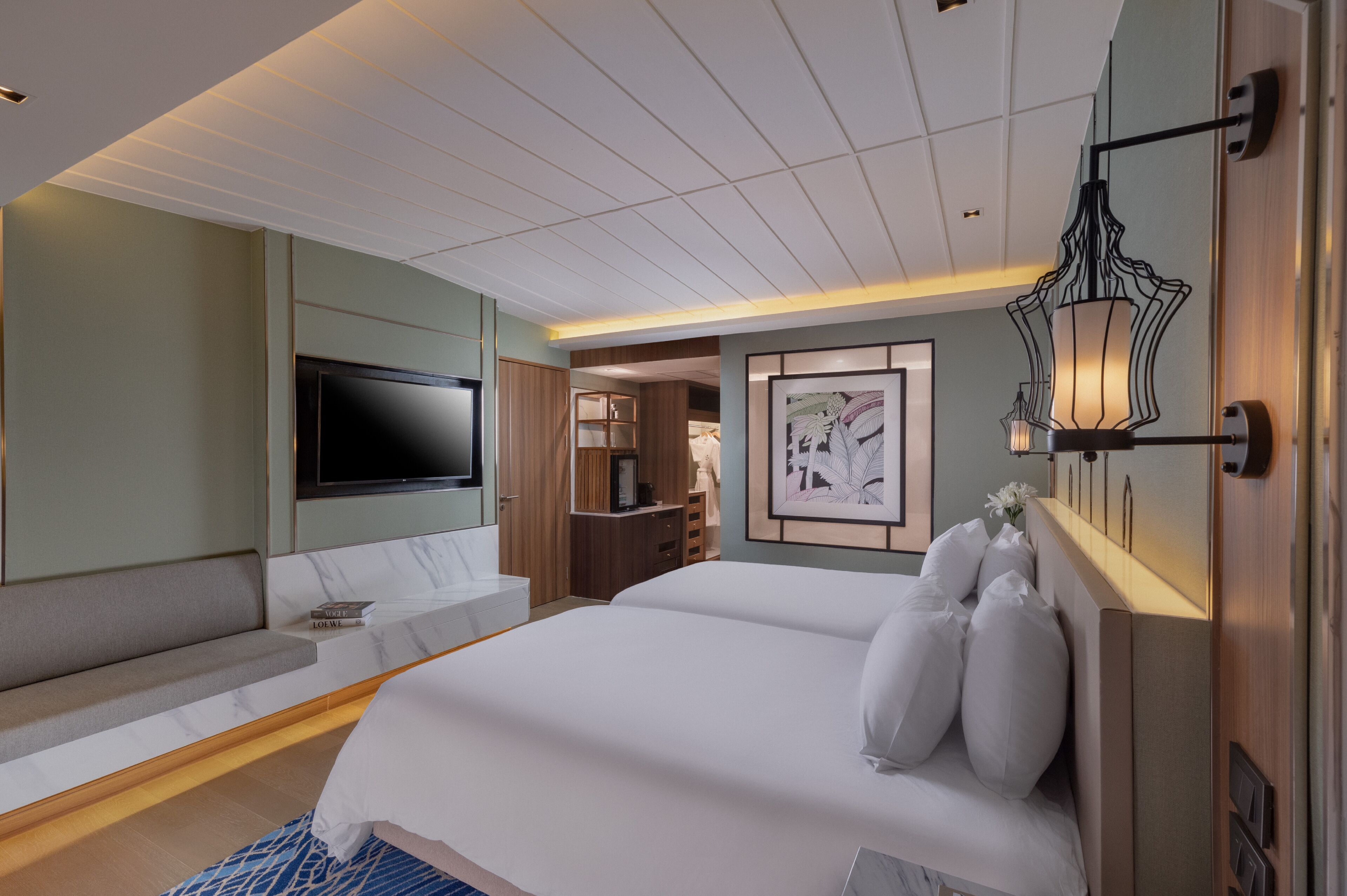 Una habitación de hotel moderna con una cama grande, un televisor de pantalla plana montado en la pared, un espacio de descanso con un sofá y un escritorio con una silla.