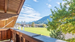 Un balcón de madera con vistas a un pueblo y montañas.
