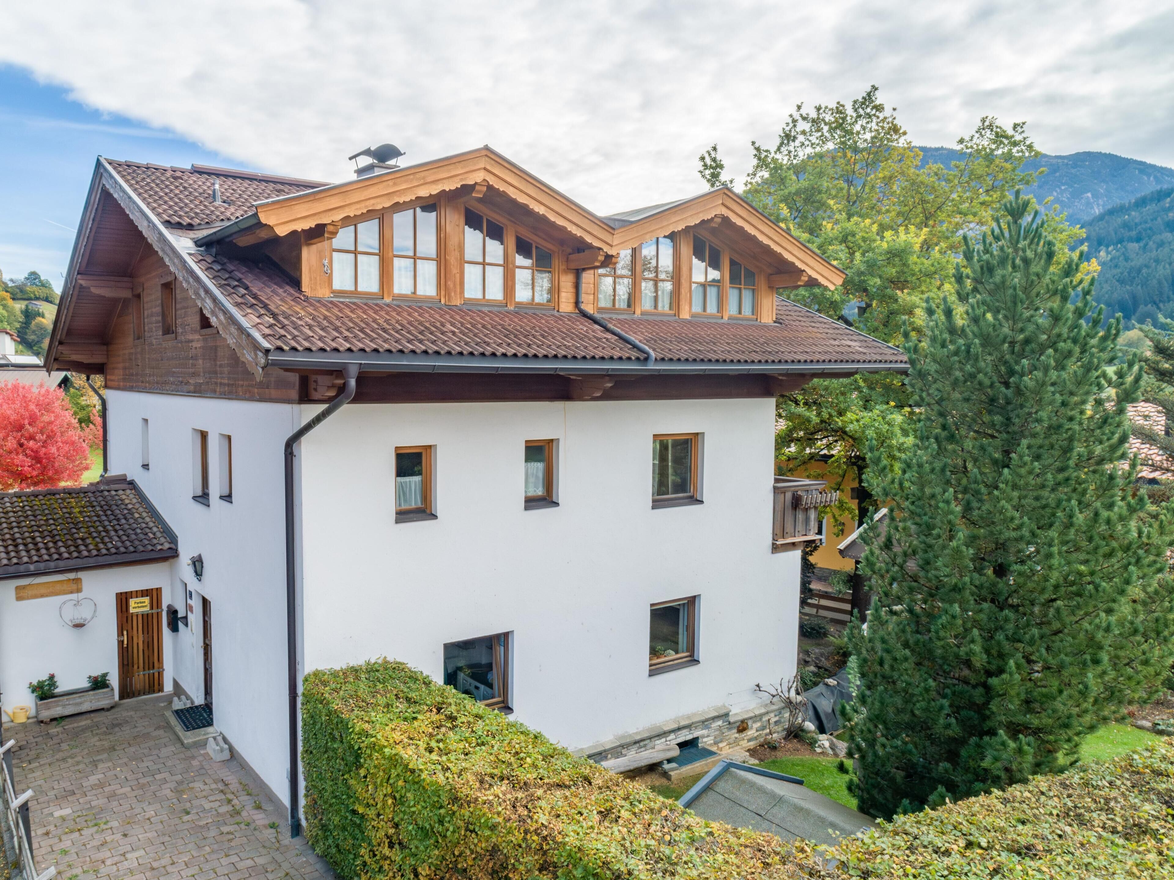 A two-story house with a sloped roof, white exterior walls, and multiple windows.