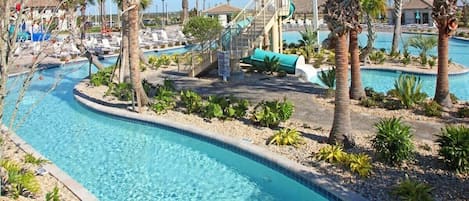 Uma área de piscina com várias piscinas, palmeiras e um toboágua.