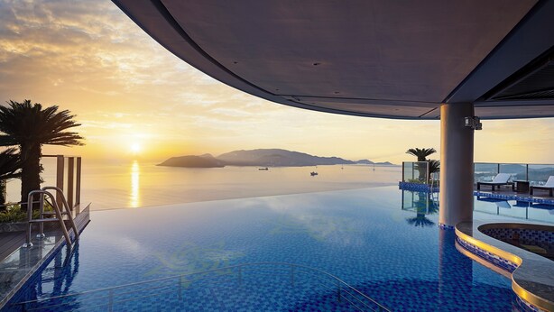 An infinity pool with a clear view of the sunset over the water, palm trees, and lounge chairs. - Best Western Premier Marvella Nha Trang (Nha Trang)